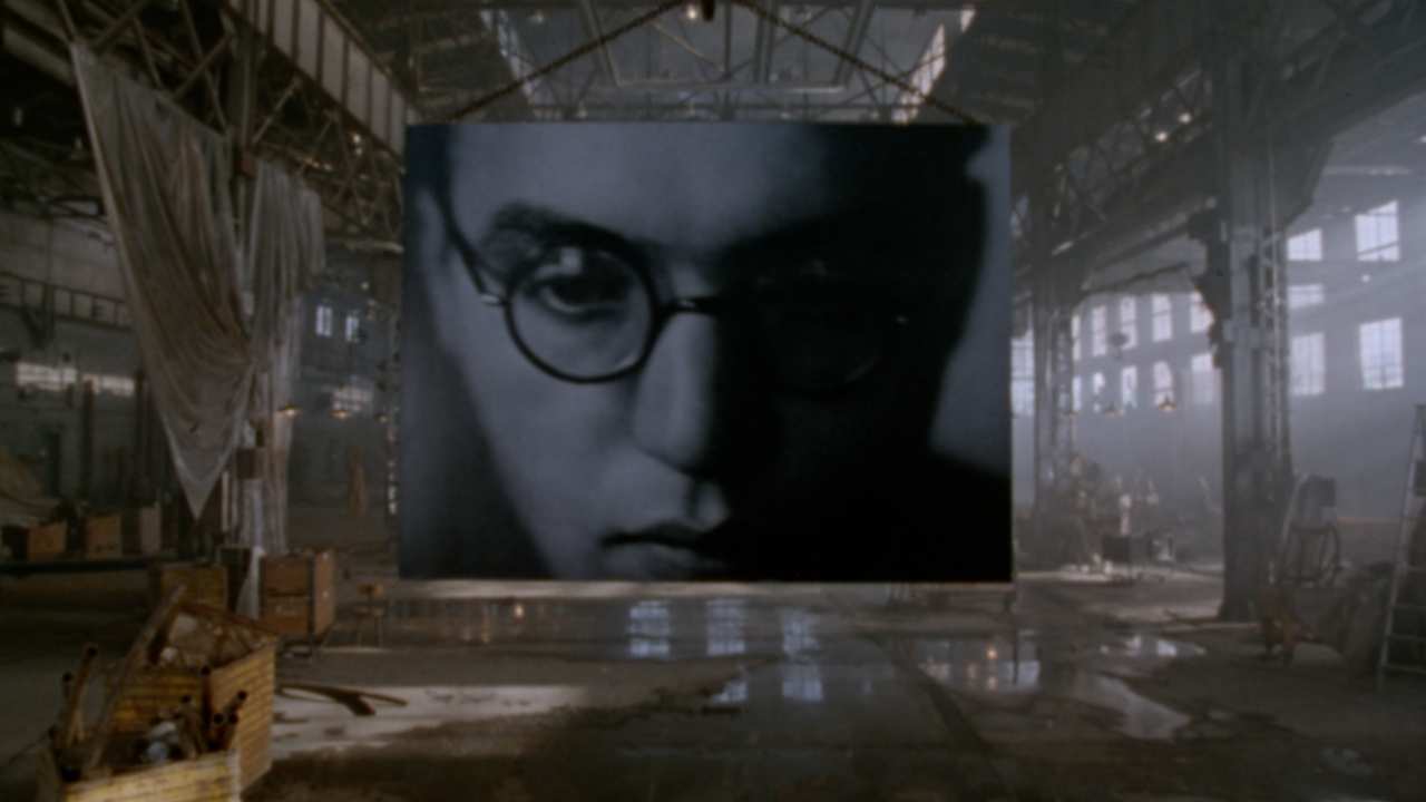 a mans face on a screen in a warehouse
